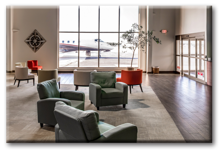 Corporate Wings FBO location in South Bend, Indiana, highlighting over-sided windows overlooking the runway, modern green and orange chairs and hardwood flooring.